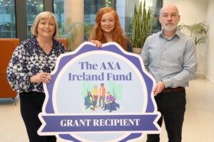 3 AXA Ireland Fund partners stand behind a large cardboard cut-out that reads "The AXA Ireland Fund" "Grant Recipient" 