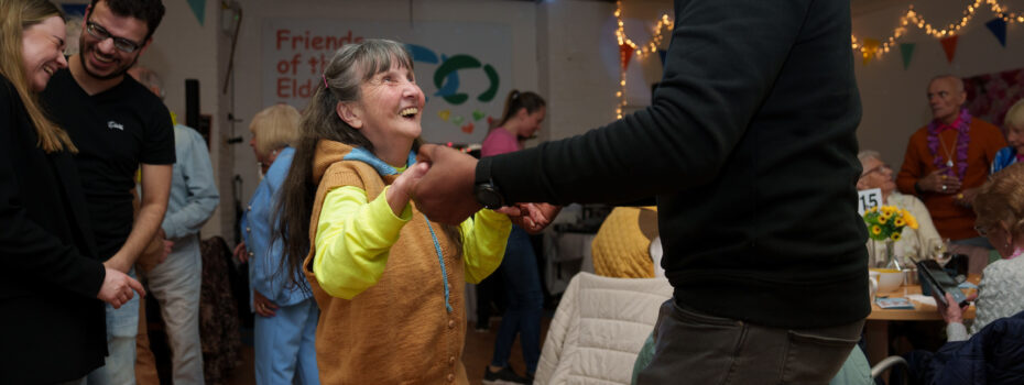 An older woman and a younger man joyfully dance together at a lively community event.