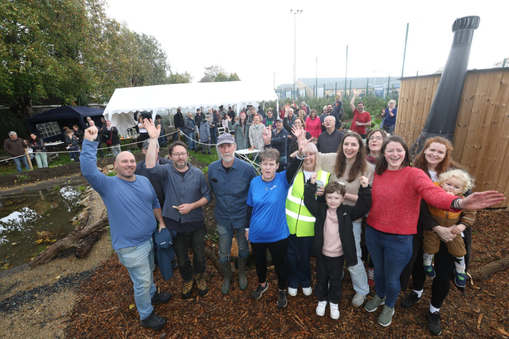Large group of people in a garden setting. They are looking and waving at the camera. This is one of the 300 communities taking biodiversity action, supported by Community Foundation Ireland