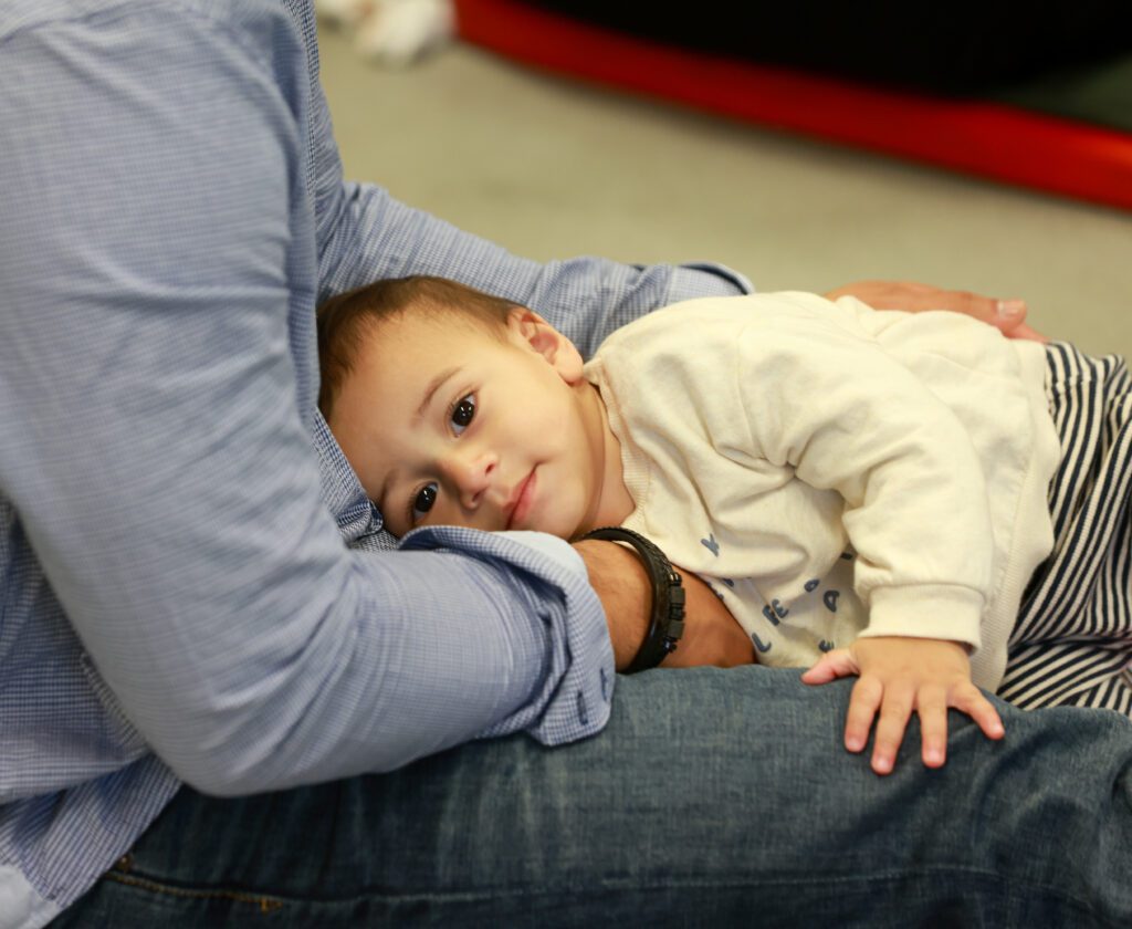 A child resting with their head down on an adults map. The young child is wearing a white top.