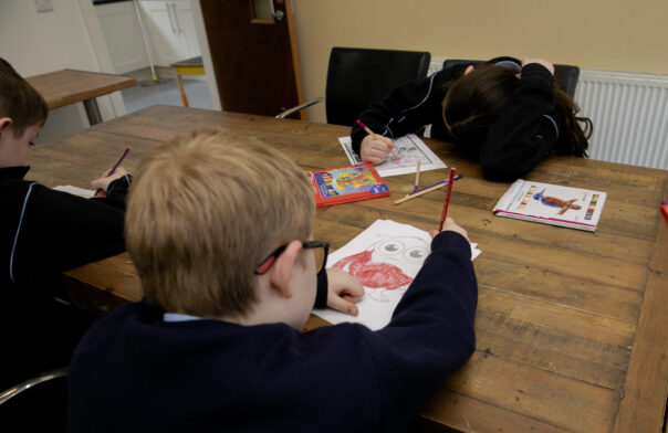 Two young children sitting at a table colouring.