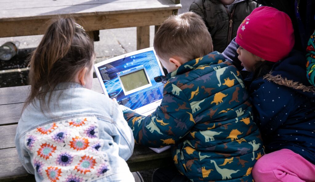 Three young children at a Community Foundation Ireland partner project. The three are engaged with an electronic toy.