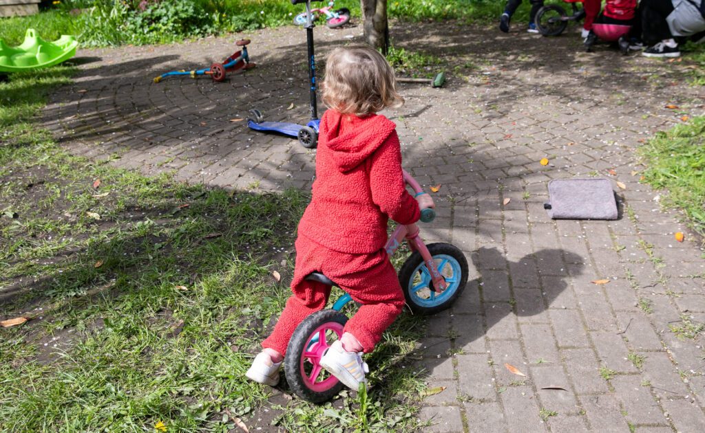 A child on a bike facing away from the camera, cycling through a play area at a partner project of Community Foundation Ireland.