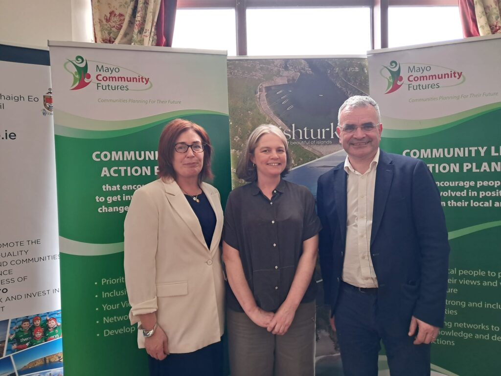 Three people standing in front of banners for 'Mayo Community Futures'. Ailbhe McEntee of Community Foundation Ireland is in the centre, or her left is Minister Dara Calleary TD.