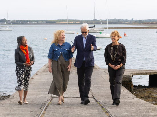Four delegates of the global summit of community foundation leaders in Malahide in Dublin. They are walking on a slipway with the sea as backdrop.