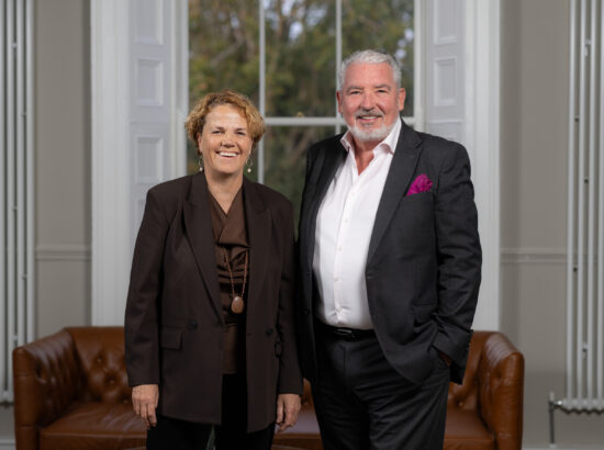 A woman and a man in business attire. They are standing in an office environment, against the backdrop of a window. Chief Executive, Denise Charlton is welcoming new Chair of Community Foundation Ireland, John Cunningham.