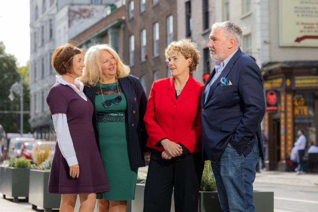 A photo of three women and a man in conversation on a street in Dublin, with office buildings as a backdrop. This is the leadership of the SERP Institute in conversation with Denise of Community Foundation Ireland